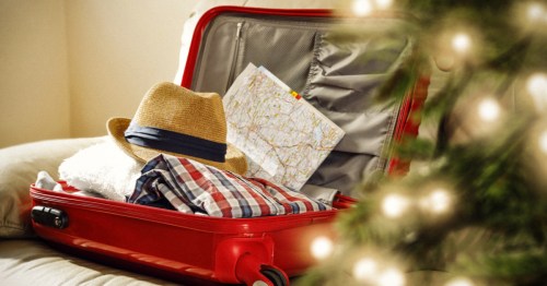 A red suitcase packed with a map near a Christmas treefor holiday travel.