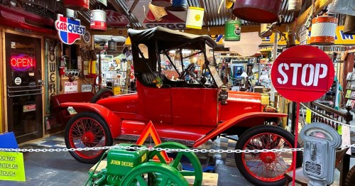 A booth inside 49 Antique & Flea Market, a massive flea market in MS, featuring a red vintage car, tools, old-fashioned signs, and more.