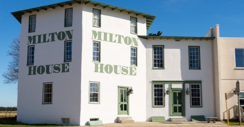 The white Milton House building with green text saying "Milton House" on the side of it