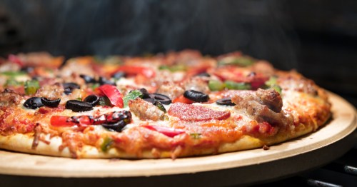 A steaming hot pizza fresh from the oven, loaded with sausage, olives, and red bell peppers.