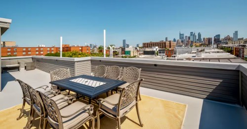 Massive roof deck with a dining table and city skyline views at The Newbold Group Hub.
