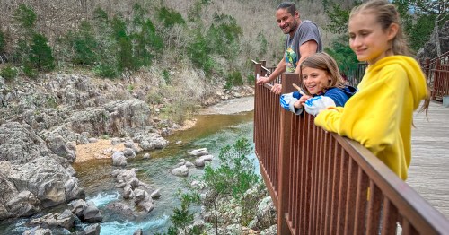 A happy family leaning over the river overlook rails at Johnson's Shut-Ins State Park in Missouri.