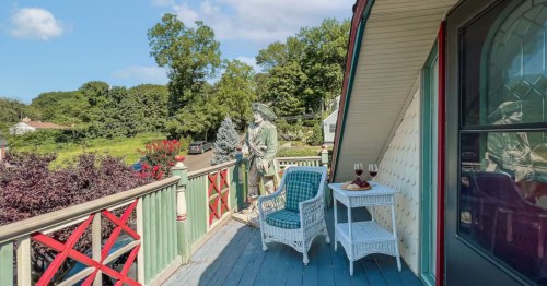 A backyard view from a porch, with several deck chairs and a green statue of a sea captain.