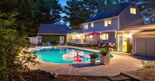 A nighttime shot of the illuminated pool at the Gorgeous Luxurious Family Villa Airbnb property in Foxborough, Massachusetts.