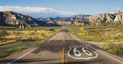 A sunny view of historic Route 66 with mountains in the background.