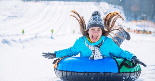 woman with long hair laughing on a snow tubing hil in illinois