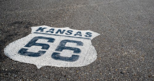 Looking down at a painted Kansas Route 66 sign on the pavement.