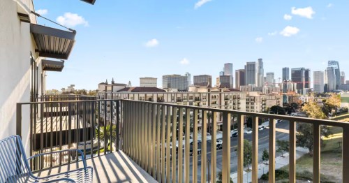 Chairs sit on a small private balcony, the Los Angeles skyline is in the distance.
