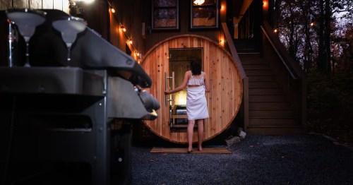 A nighttime view of a woman entering the six-person cedar-barrel sauna at the Mont Blanc Chalet Airbnb property in Mount Harmony, Pennsylvania.