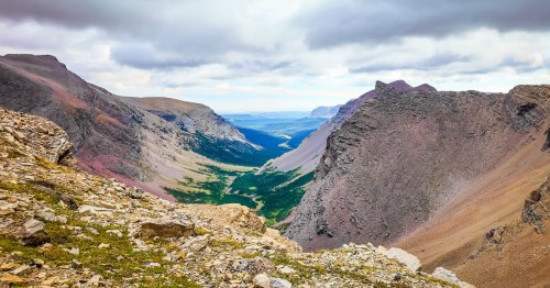 Looking toward a deep valley and rugged mountains along the Siyeh Pass Trail in Montana.