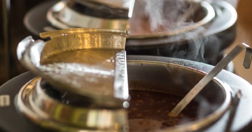 Close-up of steaming, homemade soup in a large metal serving pot with a ladle at a Montana buffet.