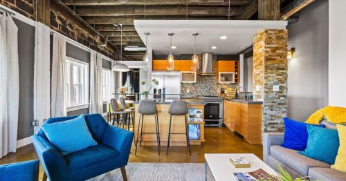 The living room of a penthouse with a blue chair.