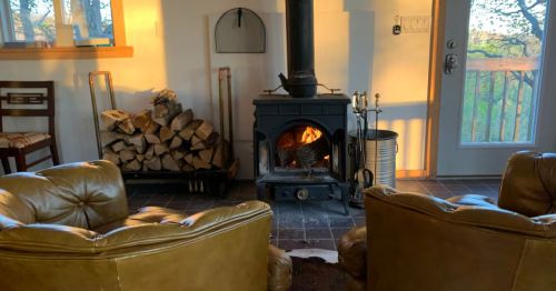 A wood-burning stove in a living room with chairs.