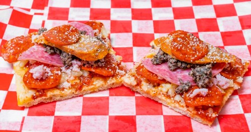 Meat pizza cut into squares served on red and white checkered paper at the oldest pizza restaurant in Miami, Florida.