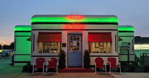The front of the Boots Court motel at dusk lit with green and red lights.