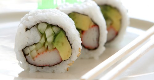 Three pieces of California roll sushi on a white plate