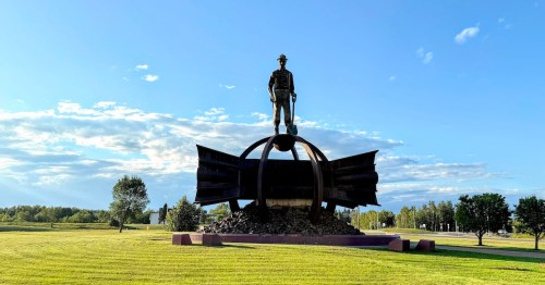 The massive Iron Man Memorial statue stands atop a pedestal in Chisholm, Minnesota, honoring the iron ore miners of the Iron Range.