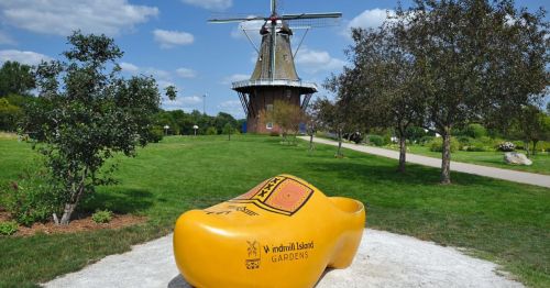 A large yellow shoe sculpture in front of a windmill.