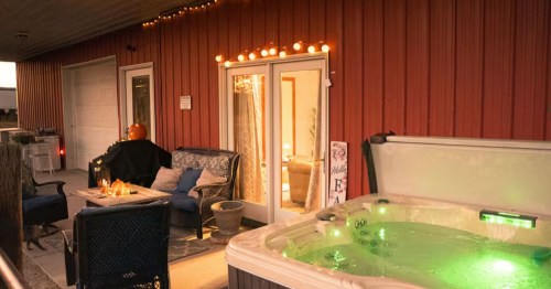 A private balcony featuring a bubbling hot tub with scenic views of the surrounding trees and nature.