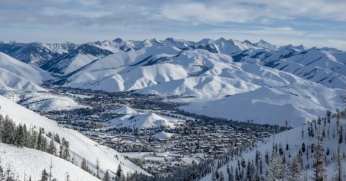 Mountains blanketed in snow surround a town caught in a small valley between the numerous peaks.