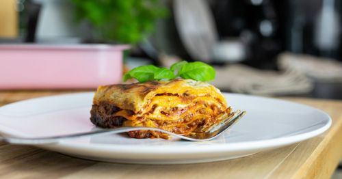 A piece of lasagna with a fork on a plate.