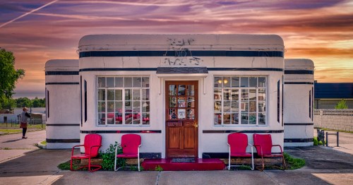 Boots Court motel at dusk with no lights on and four red chairs out front