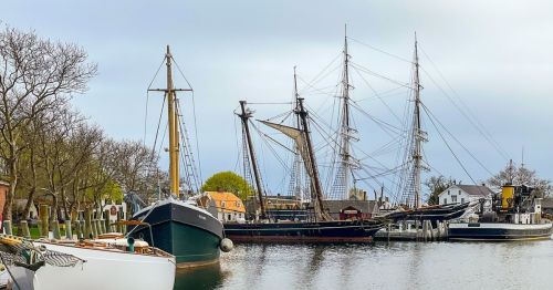 Large historical wooden ships in a port.