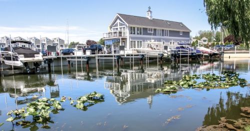A boat harbor with a white boathouse in the background.