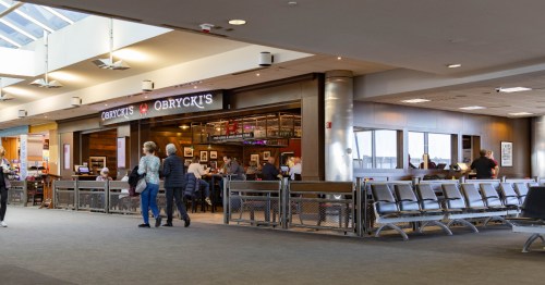 two people walk past obrycki's, a restaurant at the bwi airport
