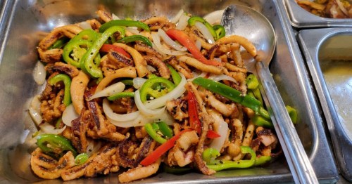 a steel pan with an asian stir fry dish at La Patrona Asian Sushi Buffet