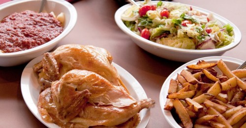 white dishes of pasta covered in sauce, roasted chicken, salad, and french fries sit on a table at. wright's farm in rhode island