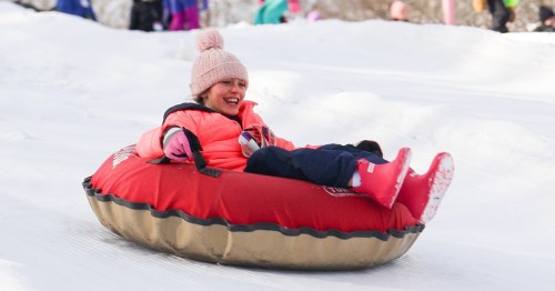 a young girl smiles as she snow tubes down a hill at yawgoo valley in rhode island