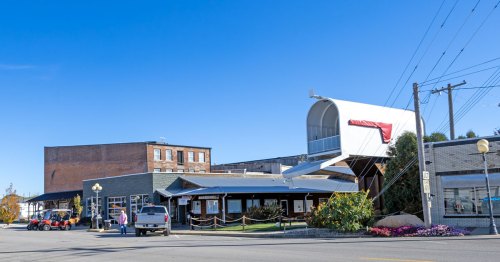 A town street is lined with buildings and a giant mailbox.