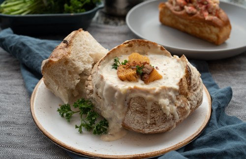 A bread bowl of clam chowder on a plate