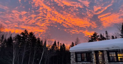 A snow-covered European-style tea house Airbnb under an orange sunset sky.