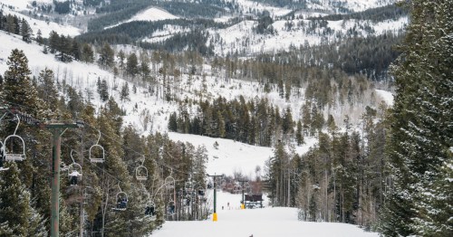 ooking downhill at Montana’s Bear Paw Ski Bowl, with the mountains in the distance and the chairlift and skiers in the foreground