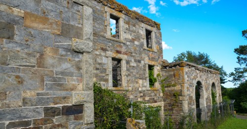 A roofless stone mansion from the 1850s with vine-draped walls and arched windows overlooking Casco Bay.