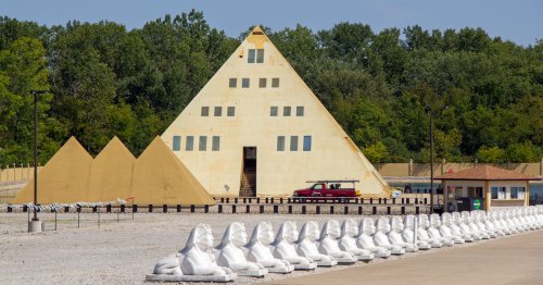 A Gold pyramid stands with three smaller pyramids and many Egyptian statues.