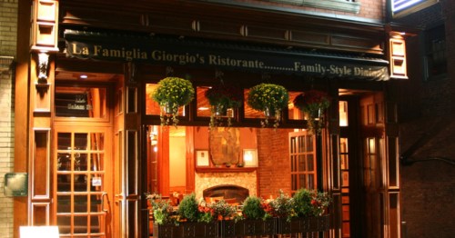 A nighttime exterior view of the illuminated La Famiglia Giorgio's Ristorante in the North End of Boston, MA. The well-known Italian restaurant holds several intense food challenges.