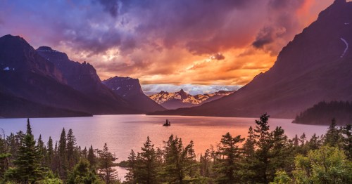 A fiery sunset is over a large mountain lake in Glacier National Park.