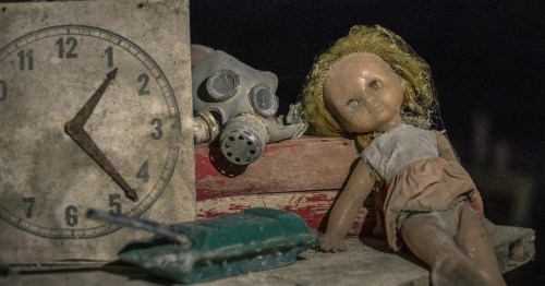 Creepy vintage doll, gas mask, and old clock on a shelf at the Museum of Shadows, a haunted museum in Omaha, Nebraska.