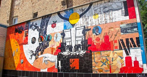 A colorful mural of red, black, and white decorates a brick wall.