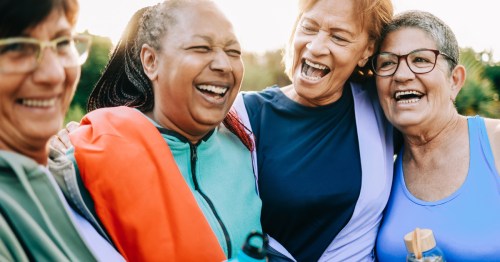 A diverse group of senior women laughs together outdoors in a sunlit Pennsylvania park setting.