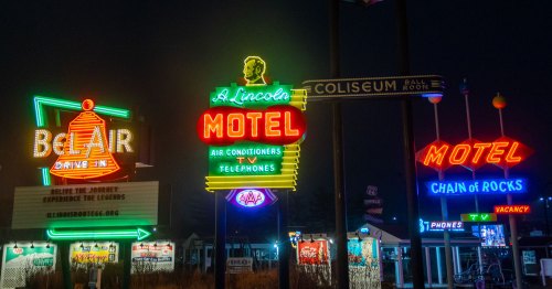 Neon signs glow in a park at night.