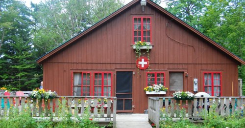 Swiss chalet in Eden, VT with red window boxes and a Swiss cross emblem. A perfect international dupe.