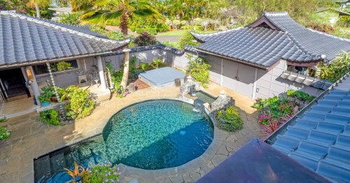 An aerial view of a Princeville, Hawaii, Airbnb with a koi pond, Balinese-style architecture, and tropical landscaping.