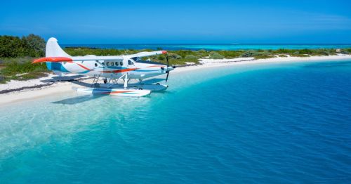 Views of a seaplane at Dry Tortugas Beach, surrounded by powdery white sand and striking turquoise blue waters.