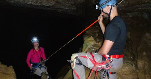 Two spelunkers wearing safety gear and harnesses inside a dark passageway at Ellison’s Cave in Georgia.