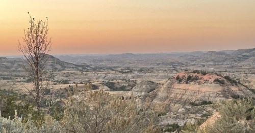 Vivid pink and orange sky at dusk, highlighting the majestic colors of North Dakota over the Badlands.