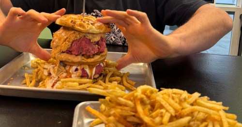 A man holds a giant roast beef sandwich with tallow fries at Bene's Beef in Maine.